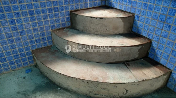Posisi trap tangga membulat di sudut kolam renang.